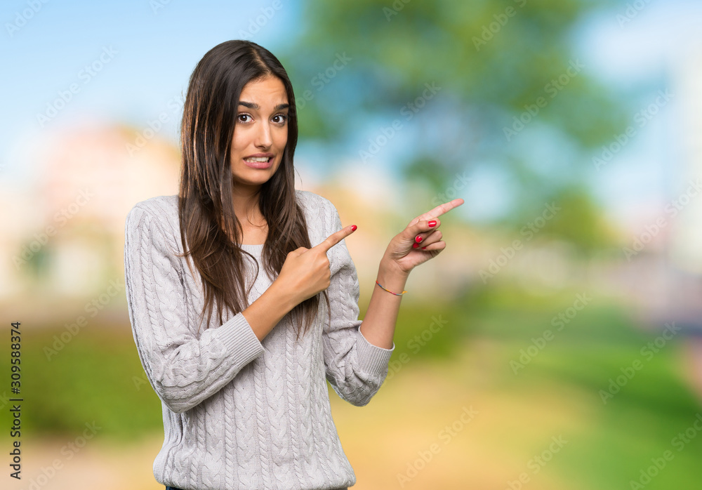 Young hispanic brunette woman frightened and pointing to the side at outdoors Young hispanic brunette woman frightened and pointing to the side at outdoors