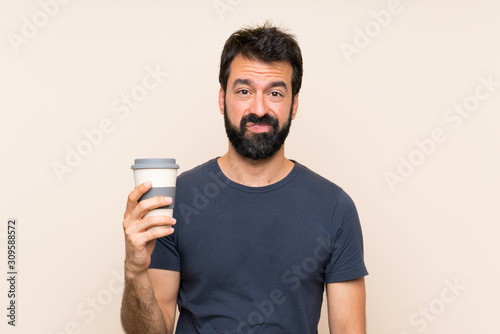 Man with beard holding a coffee with sad expression