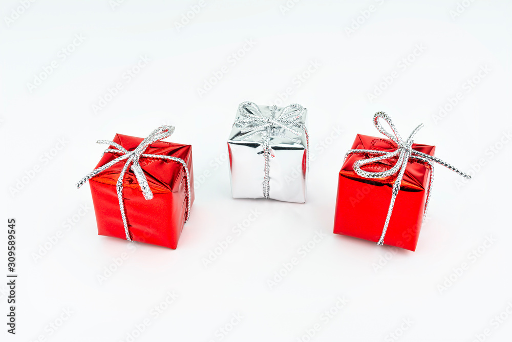 Macro picture of two red and one silver, shiny wrapped gift with bow, isolated on a white background. Macro picture of two red and one silver, shiny wrapped gift with bow, isolated on a white background.