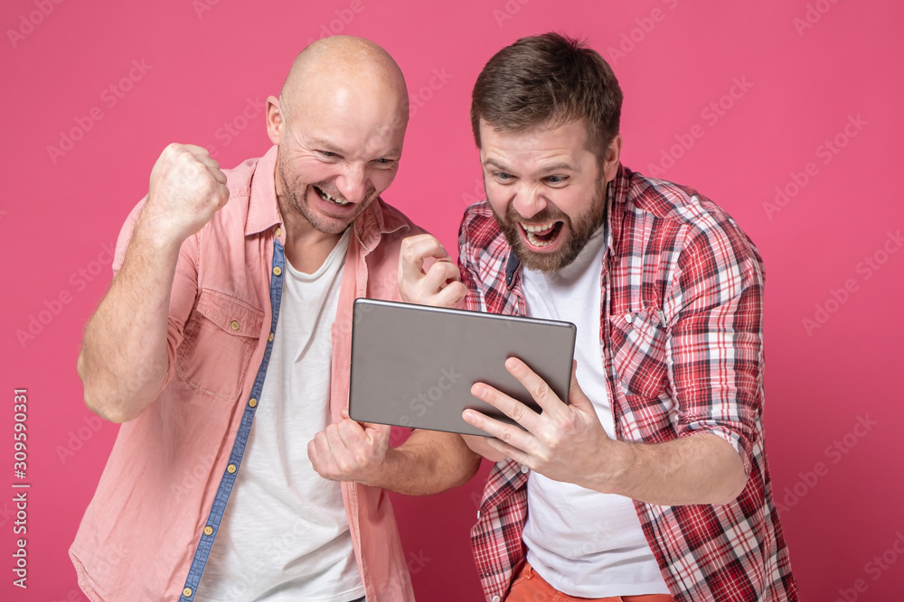 Φωτογραφία Friends rejoice at good sports news that look on the tablet screen, they raise their hands up and scream loudly