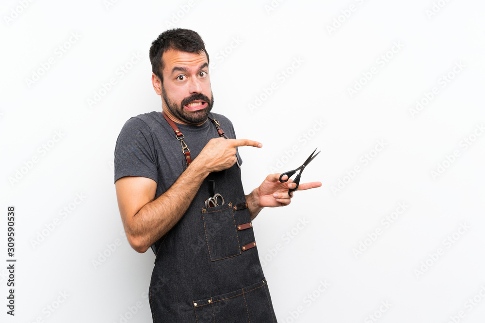 Barber man in an apron frightened and pointing to the side