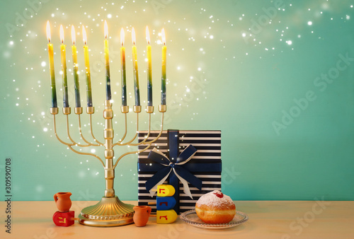 religion image of jewish holiday Hanukkah with menorah (traditional candelabra), spinning top and doughnut over wooden background