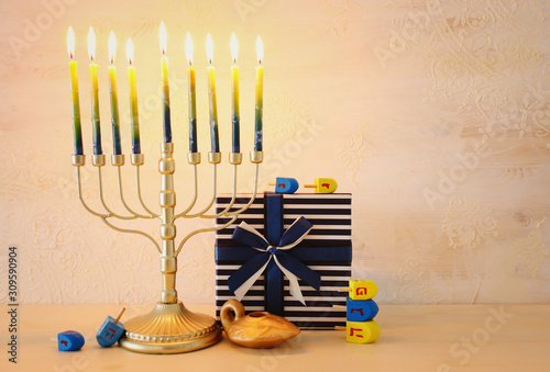 religion image of jewish holiday Hanukkah with menorah (traditional candelabra), spinning top over wooden background