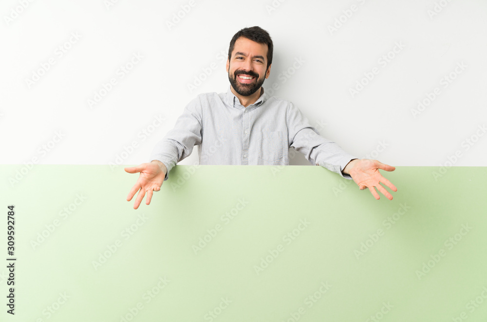 Young handsome man with beard holding a big green empty placard smiling Young handsome man with beard holding a big green empty placard smiling