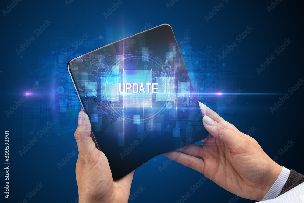 Businessman holding a foldable smartphone with UPDATE inscription, new technology concept Businessman holding a foldable smartphone with UPDATE inscription, new technology concept