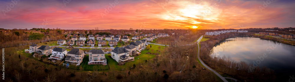 Aerial sunset panorama view of luxury upscale residential neighborhood gated community single family homes with decks and gazebos manicured green lawn lake view East Coast USA, American real estate 