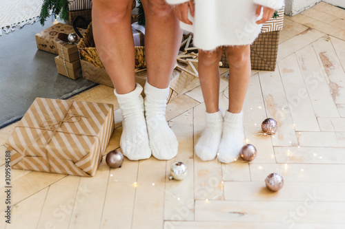 Girl with mom feet gifts, balls, Christmas tree and interior, Christmas and new year