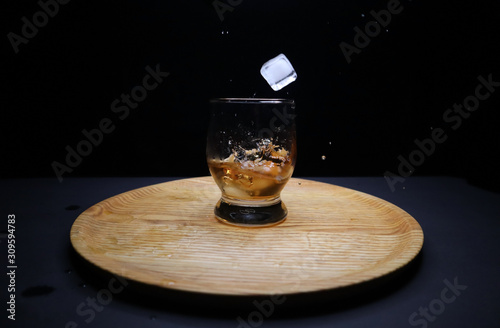 glass of whiskey and ice on black background