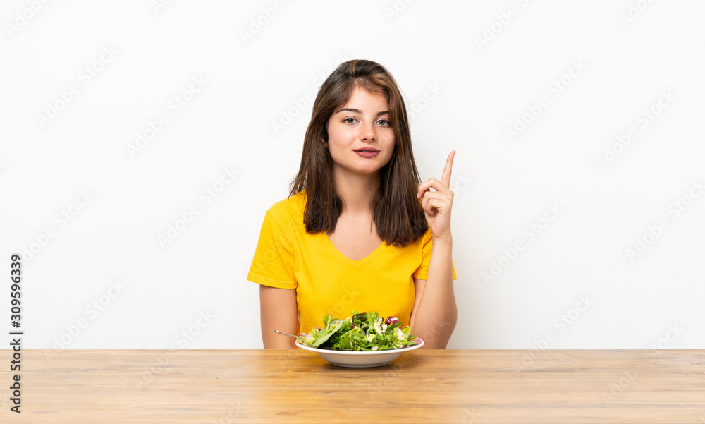 Caucasian girl with salad pointing with the index finger a great idea Caucasian girl with salad pointing with the index finger a great idea