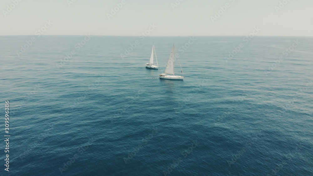 Obraz premium Aerial View of yacht in ocean. Drone footage of yachting around Balearic islands in the mediterranean sea. Silhouette of people