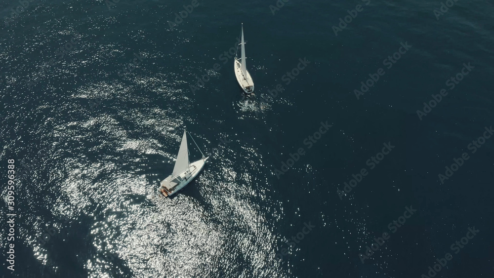 Aerial View of yacht in ocean. Drone footage of yachting around Balearic islands in the mediterranean sea. Silhouette of people