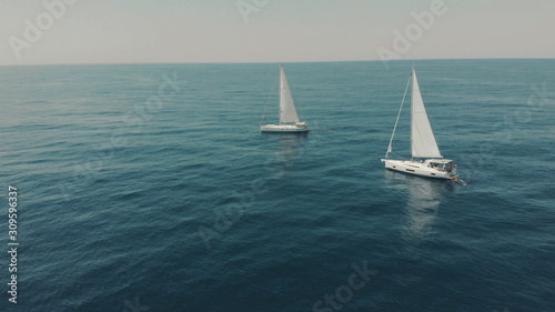 Aerial View of yacht in ocean. Drone footage of yachting around Balearic islands in the mediterranean sea. Silhouette of people