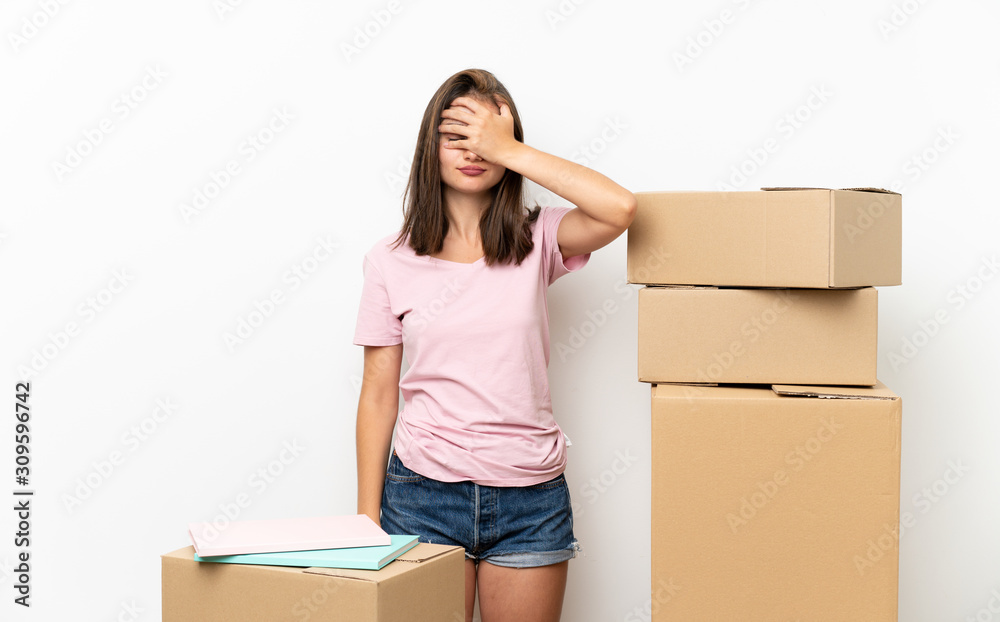 Young girl moving in new home among boxes covering eyes by hands Young girl moving in new home among boxes covering eyes by hands