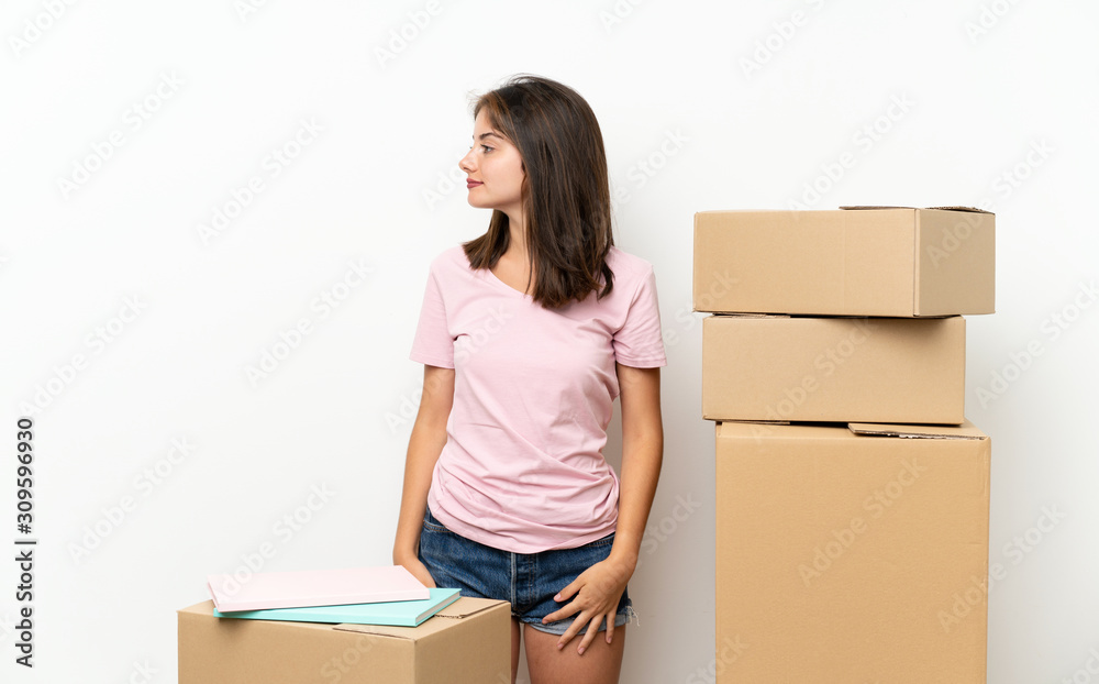 Young girl moving in new home among boxes looking to the side Young girl moving in new home among boxes looking to the side
