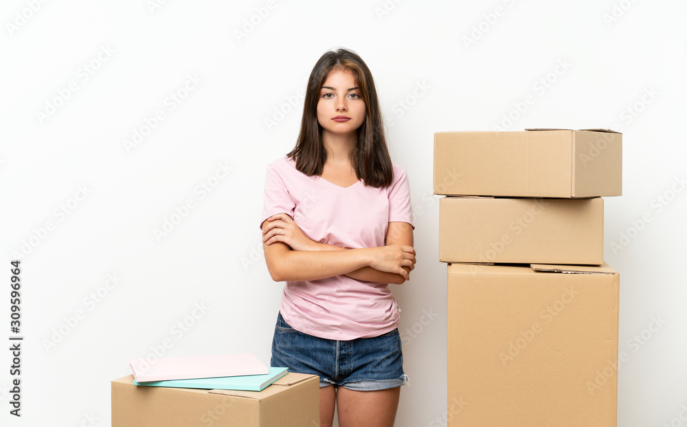 Young girl moving in new home among boxes keeping arms crossed