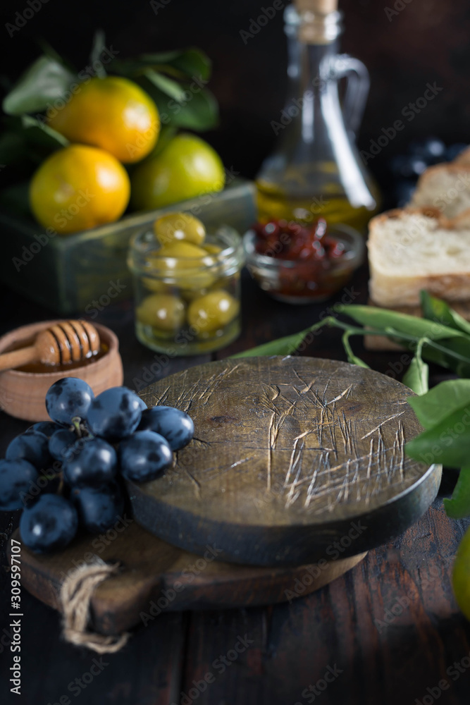 food frame made of wooden round boards, tangerines, olives, bottles of olive oil, grapes and honey. Vertical Image and Copy Space food frame made of wooden round boards, tangerines, olives, bottles of olive oil, grapes and honey. Vertical Image and Copy Space