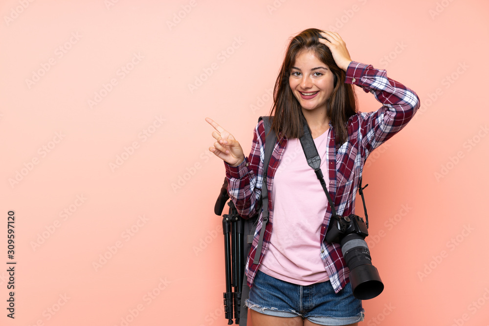 Young photographer girl over isolated pink background surprised and pointing finger to the side Young photographer girl over isolated pink background surprised and pointing finger to the side