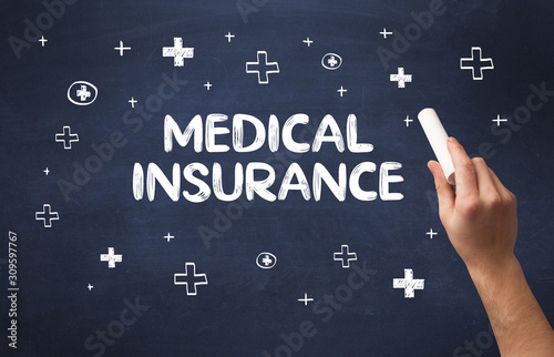 Hand drawing MEDICAL INSURANCE inscription with white chalk on blackboard, medical concept