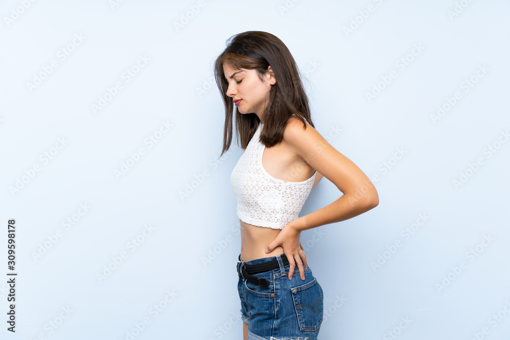 Young woman over isolated blue background suffering from backache for having made an effort Young woman over isolated blue background suffering from backache for having made an effort