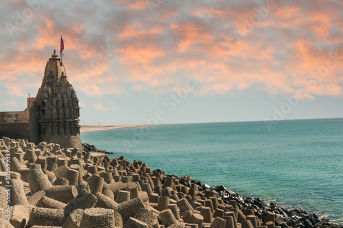 Lone hindu temple with flag on arabian sea coast with wave breakers photo