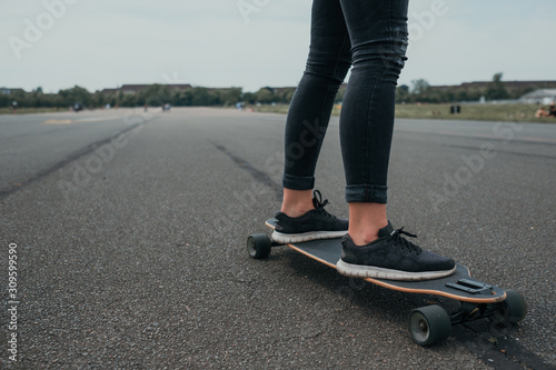 Closeup of woman's feet riding longboard on asphalt