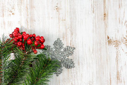 Christmas composition background decoration with fir pine tree branches snowflake and red berries on wooden white background. Flat lay, top view, copy space
