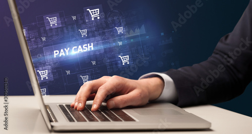 Businessman working on laptop with PAY CASH inscription, online shopping concept