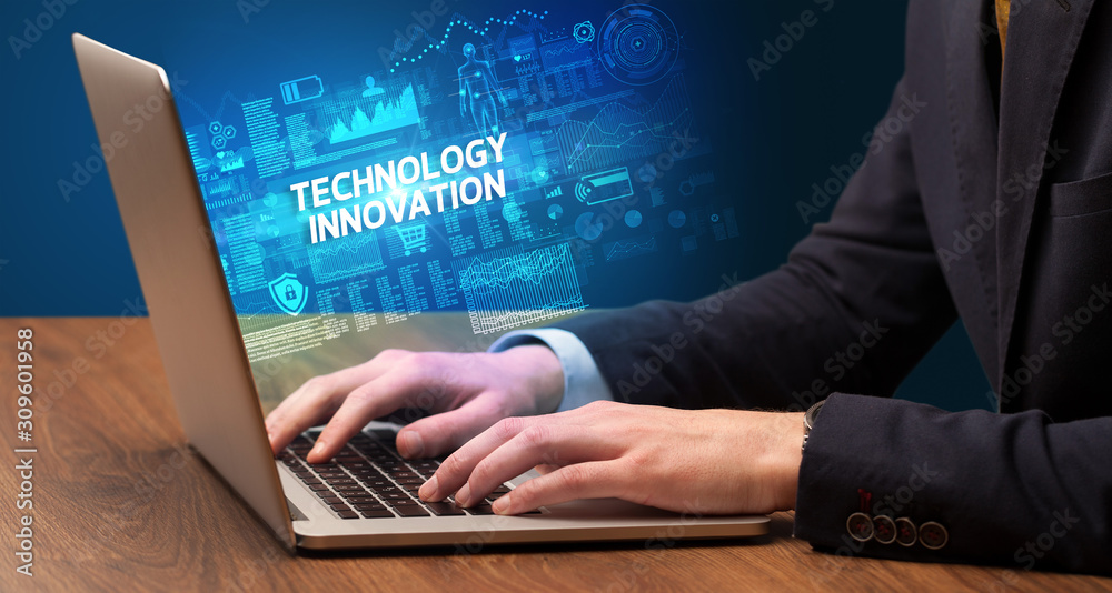 Businessman working on laptop with TECHNOLOGY INNOVATION inscription, cyber technology concept Businessman working on laptop with TECHNOLOGY INNOVATION inscription, cyber technology concept