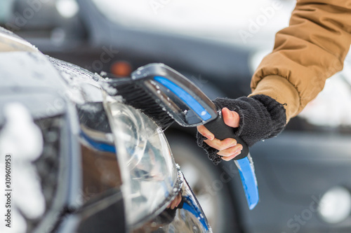 Vehicle and people concept - man cleaning snow from car with cleaning tool © mathefoto