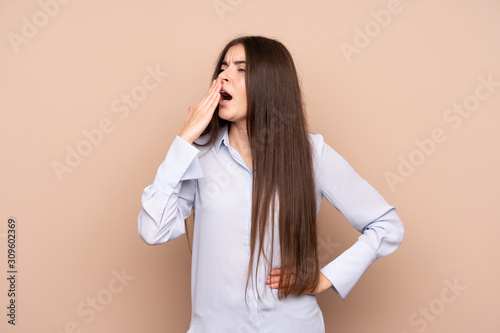 Young woman over isolated background yawning and covering wide open mouth with hand