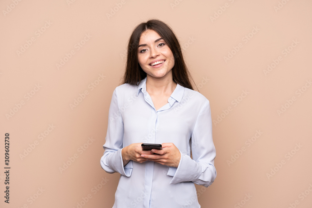 Young woman over isolated background sending a message with the mobile Young woman over isolated background sending a message with the mobile