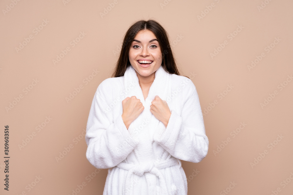 Young girl in a bathrobe over isolated background celebrating a victory Young girl in a bathrobe over isolated background celebrating a victory