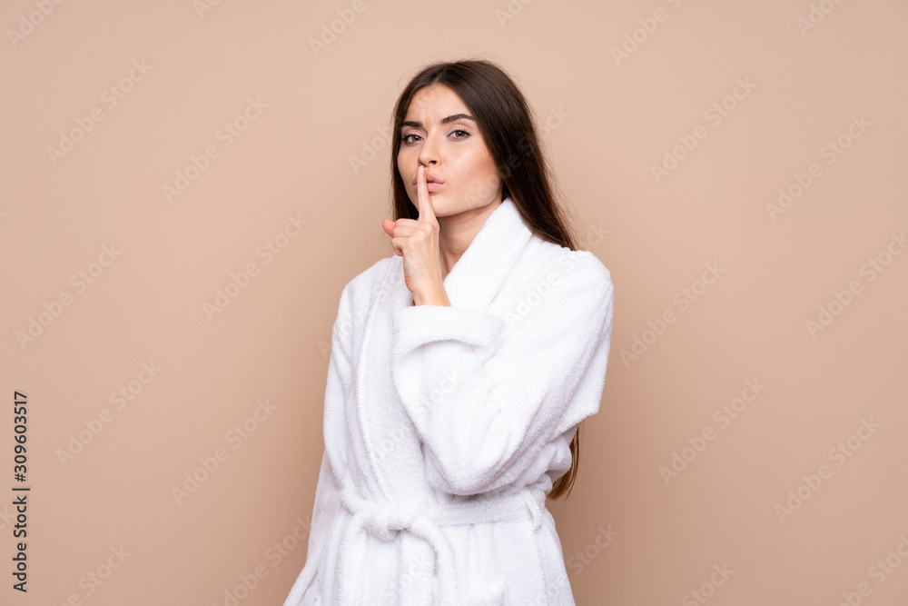 Young girl in a bathrobe over isolated background doing silence gesture Young girl in a bathrobe over isolated background doing silence gesture