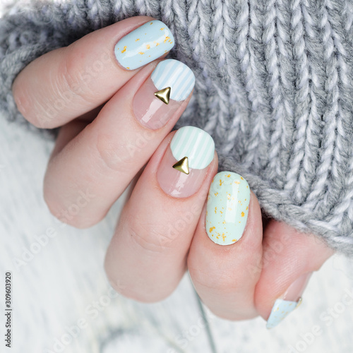 gentle mint blue manicure with gold glitter and rivets and stripes pattern