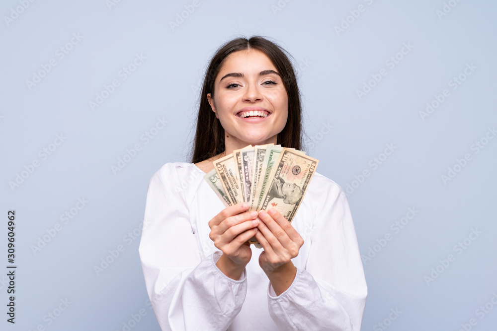 Young woman over isolated blue background taking a lot of money Young woman over isolated blue background taking a lot of money