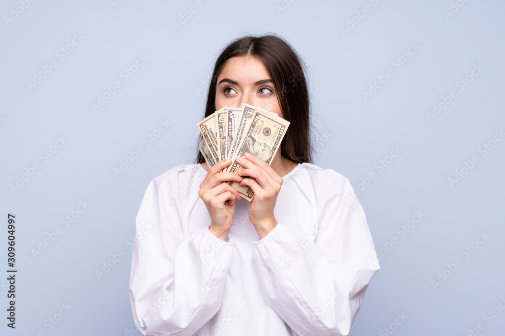 Young woman over isolated blue background taking a lot of money Young woman over isolated blue background taking a lot of money