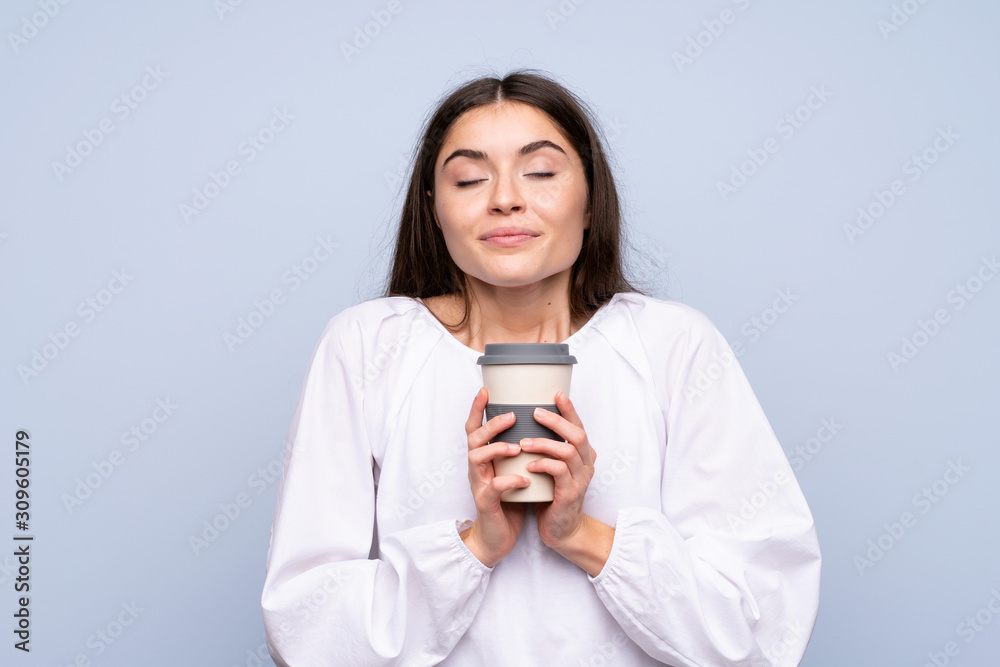 Young woman over isolated blue background holding coffee to take away Young woman over isolated blue background holding coffee to take away