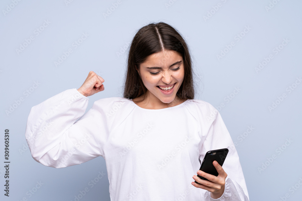 Young woman over isolated blue background using mobile phone Young woman over isolated blue background using mobile phone