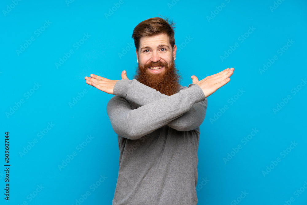 Redhead man with long beard over isolated blue background making NO gesture Redhead man with long beard over isolated blue background making NO gesture