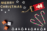 The Inscription Merry Christmas made of wooden letters, lying flat from above, isolated on a black background. Visible candy canes, wooden Christmas trees and sleds.