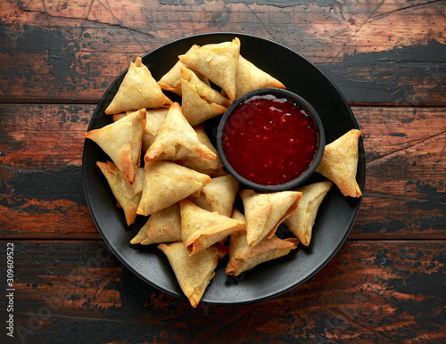 Fresh Indian Samosa with dipping sweet chili sauce on wooden table
