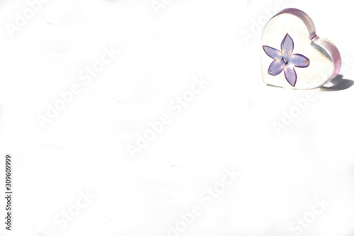 Beautiful simple heart with dried violet lilac flower. Epoxy resin heart isolated on white background situated top right. Suitable for text input.