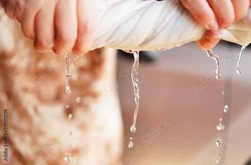 Fotografie Two hands wring wet cloth after washing by twist and squeeze
