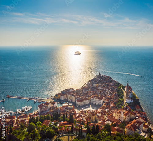 Fototapeta Naklejka Na Ścianę i Meble -  Aerial view of the old city Piran and beautiful sailing ship with five masts at sunset time. Slovenia, Europe