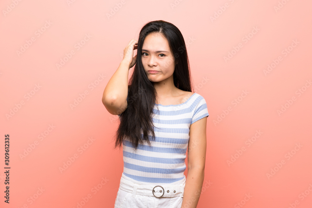 Teenager asian girl over isolated pink background having doubts Teenager asian girl over isolated pink background having doubts