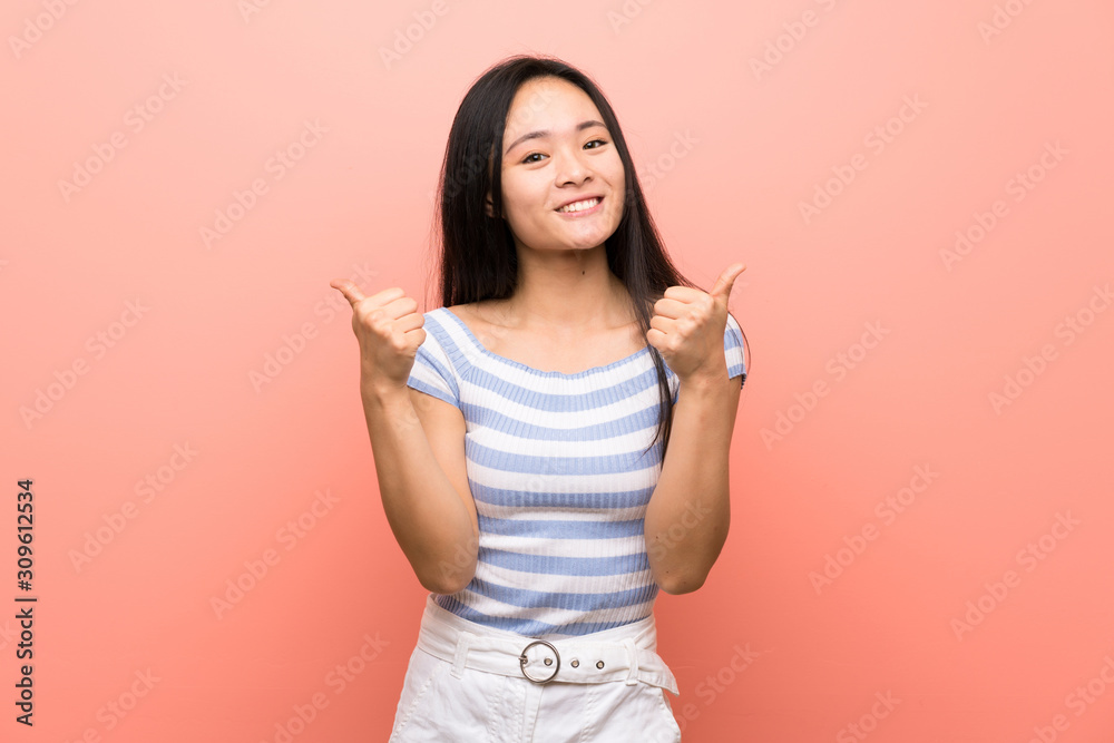Teenager asian girl over isolated pink background with thumbs up gesture and smiling Teenager asian girl over isolated pink background with thumbs up gesture and smiling