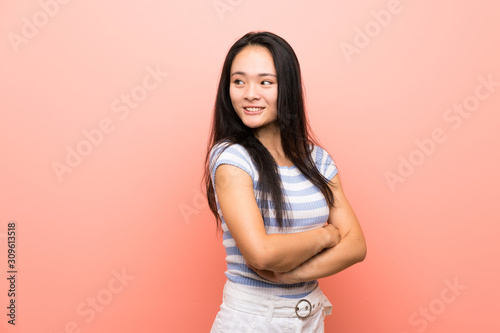 Teenager asian girl over isolated pink background with arms crossed and happy