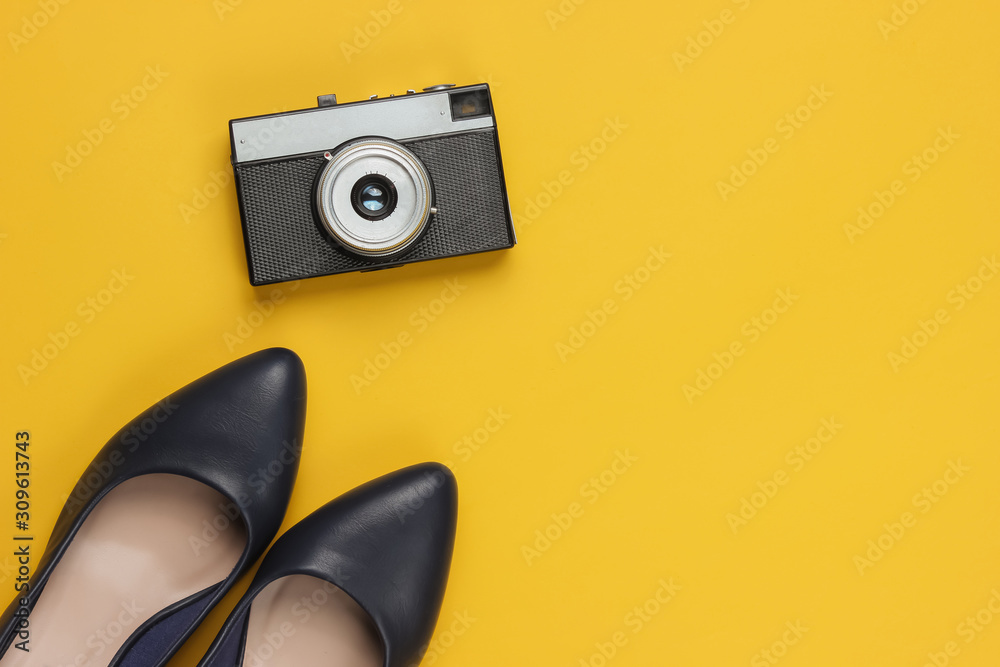 Leather high heel shoes, retro camera on yellow background. Travel concept. Trip to new cities, tourism. Top view