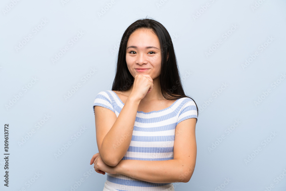 Teenager asian girl over isolated blue background laughing Teenager asian girl over isolated blue background laughing