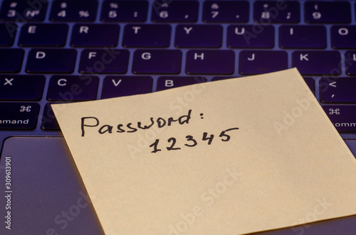 A very weak, simple and widespread password is written on a sticker that lies on the laptop keyboard. Password Security Weakness Concept. Bad password. Typical information security failures. 